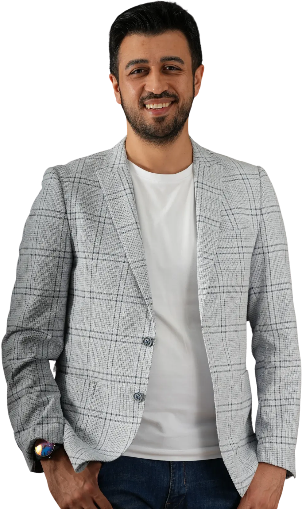 Assoc. Prof. Dr. Nesrettin Fatih Turgut smiling in a grey plaid blazer, white t-shirt, and jeans, with one hand in his pocket.